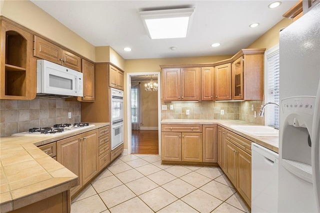 kitchen featuring a sink, white appliances, tasteful backsplash, and light tile patterned floors