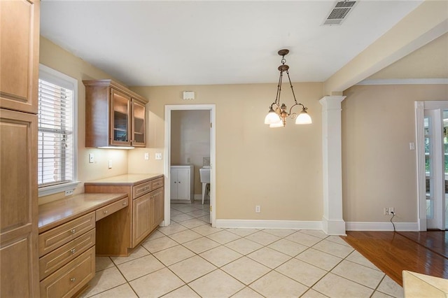 kitchen featuring visible vents, glass insert cabinets, light countertops, decorative columns, and built in study area