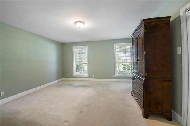 unfurnished bedroom featuring light colored carpet and baseboards