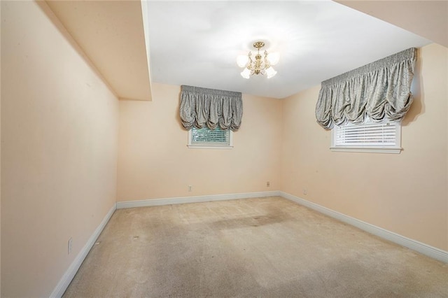 empty room featuring baseboards, an inviting chandelier, and carpet flooring