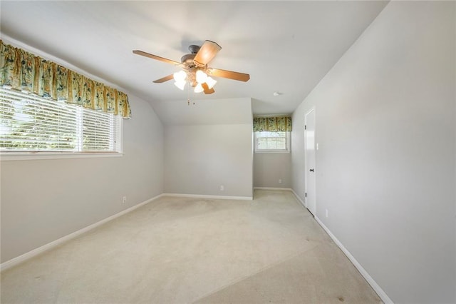 unfurnished room with lofted ceiling, light colored carpet, baseboards, and ceiling fan