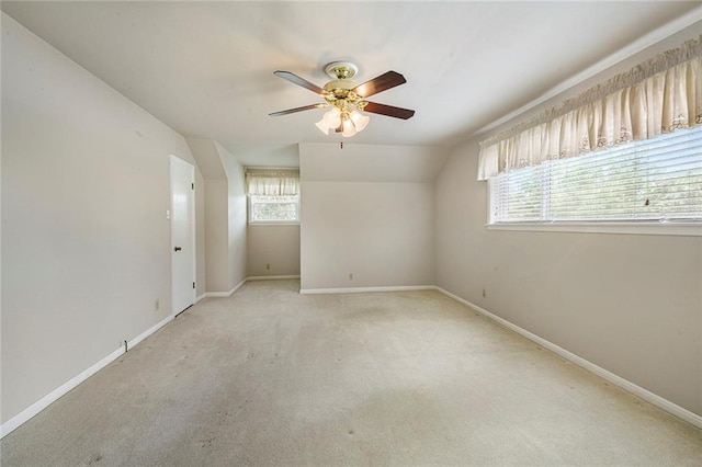 carpeted empty room with ceiling fan, lofted ceiling, and baseboards