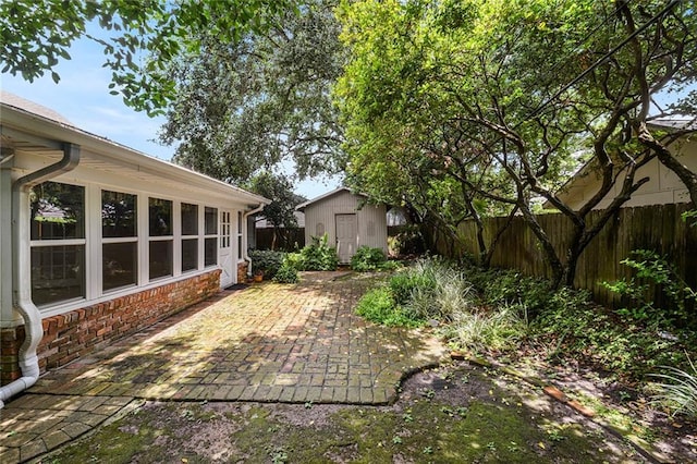 view of yard with an outdoor structure, a storage unit, a fenced backyard, and a patio area