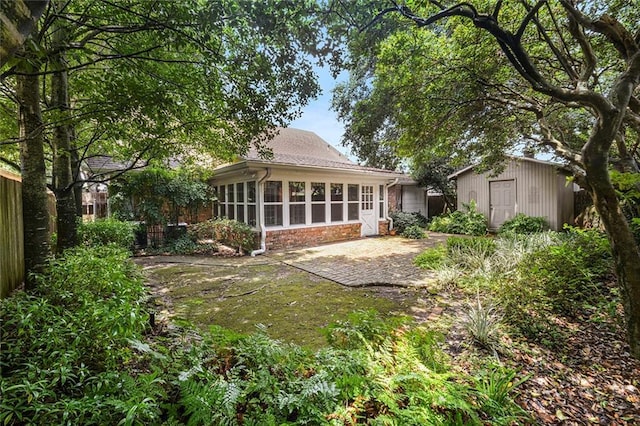 back of property with a patio, fence, a shed, an outdoor structure, and a sunroom