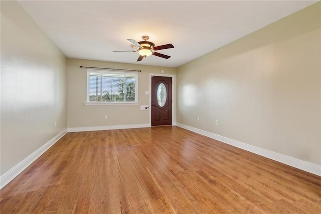 foyer entrance with light wood-style flooring, a ceiling fan, and baseboards