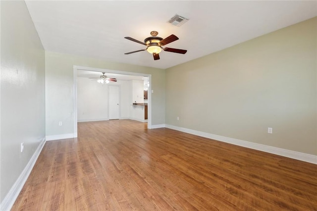 spare room featuring ceiling fan, visible vents, baseboards, and wood finished floors