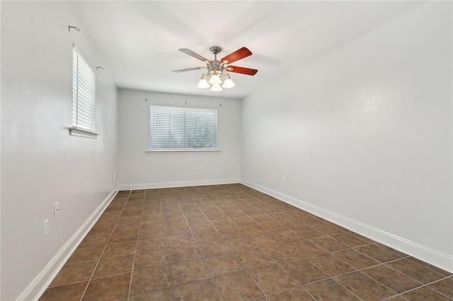 unfurnished room featuring dark tile patterned flooring, a ceiling fan, and baseboards