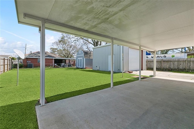 view of patio with an outbuilding, a storage unit, a fenced backyard, and a carport