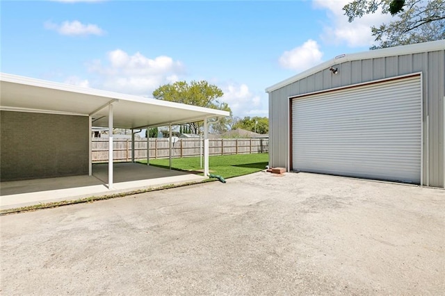 detached garage featuring driveway and fence