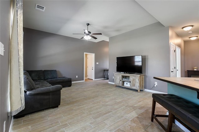 living room with light wood-style flooring, a ceiling fan, visible vents, and baseboards