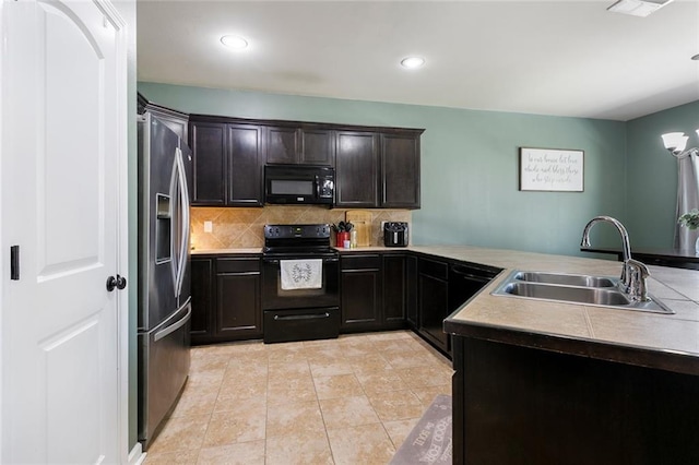 kitchen with black appliances, a sink, a peninsula, light tile patterned floors, and decorative backsplash