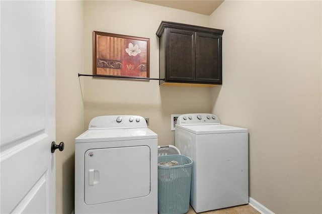 laundry area featuring washer and dryer, baseboards, and cabinet space