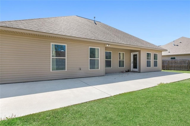 back of house featuring a yard, fence, roof with shingles, and a patio area