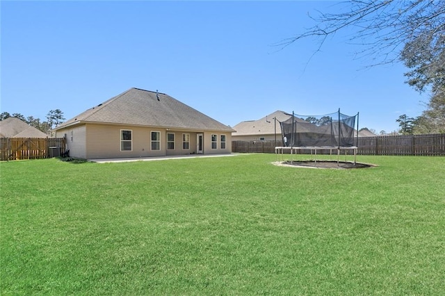 back of property with a patio area, a trampoline, a lawn, and a fenced backyard