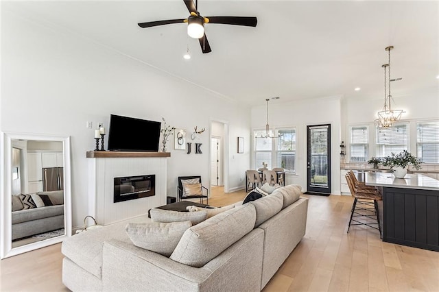 living room with a wealth of natural light, a glass covered fireplace, light wood-type flooring, and ornamental molding