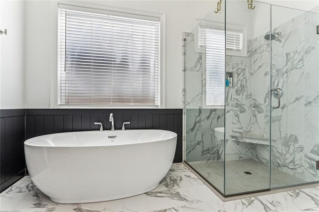 full bath featuring a wainscoted wall, a soaking tub, marble finish floor, and a marble finish shower