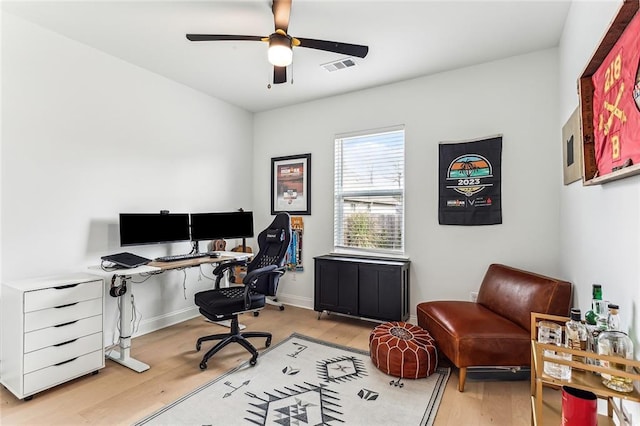 office space with light wood-style flooring, a ceiling fan, visible vents, and baseboards