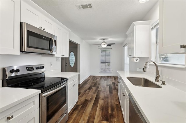 kitchen featuring stainless steel appliances, a sink, dark wood finished floors, visible vents, and white cabinetry
