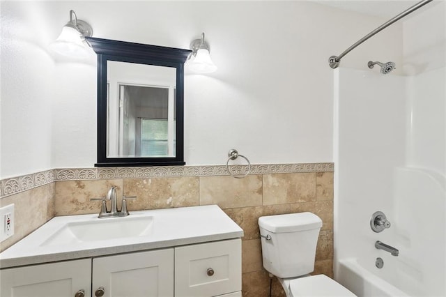 bathroom with tile walls, toilet, vanity, and a wainscoted wall