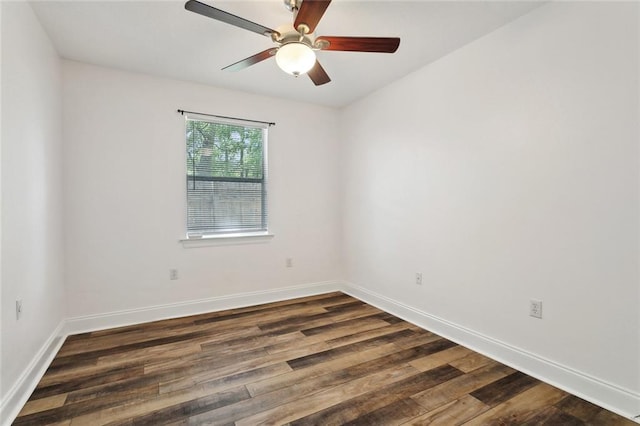 empty room featuring dark wood finished floors, baseboards, and ceiling fan