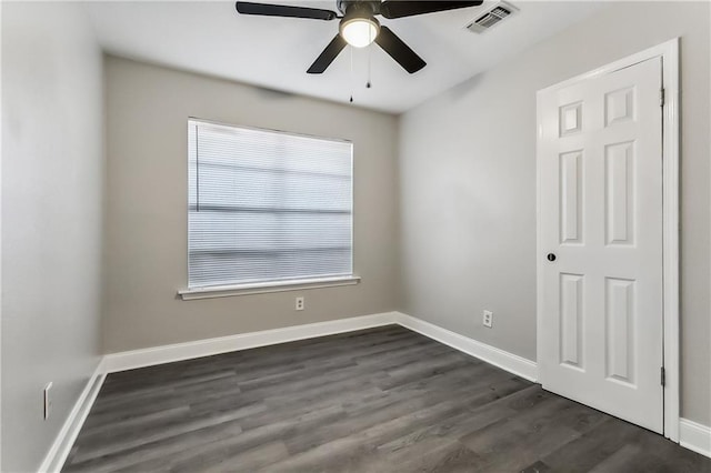 spare room featuring visible vents, baseboards, dark wood-type flooring, and ceiling fan