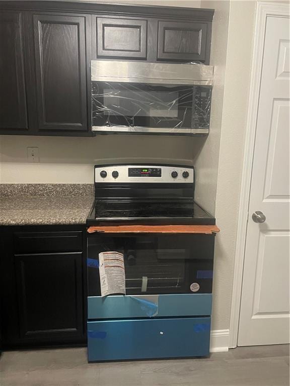 kitchen featuring dark countertops, stainless steel microwave, and range with electric cooktop