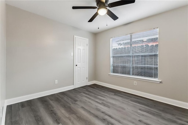 empty room with dark wood finished floors, a ceiling fan, and baseboards