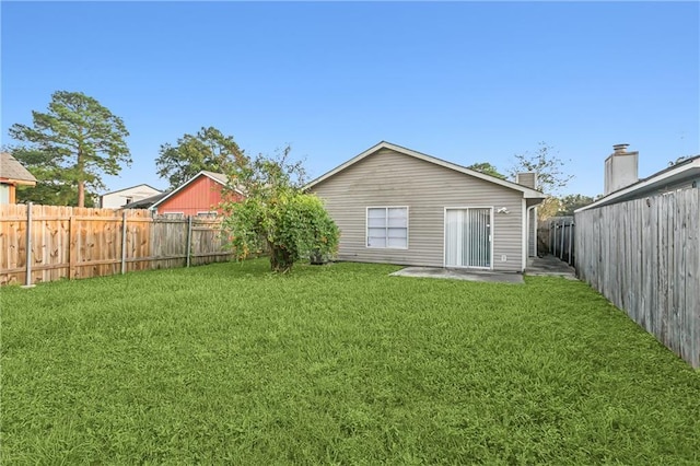 rear view of property with a yard and a fenced backyard