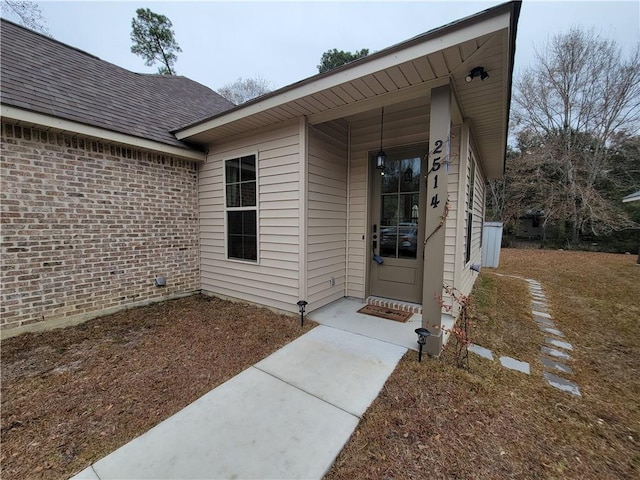 property entrance with brick siding and a shingled roof