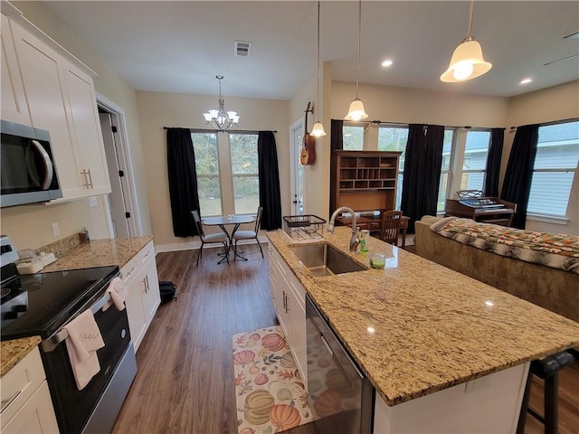 kitchen featuring dark wood finished floors, a center island with sink, appliances with stainless steel finishes, white cabinetry, and a sink