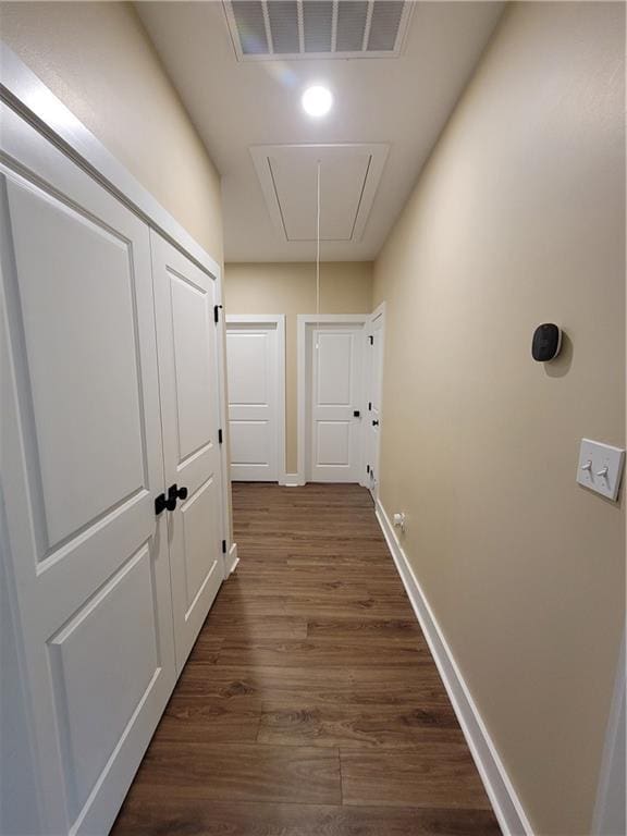 corridor featuring attic access, dark wood-style floors, visible vents, and baseboards