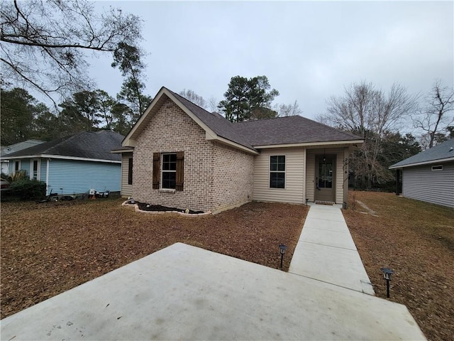 single story home with brick siding, roof with shingles, and a patio area