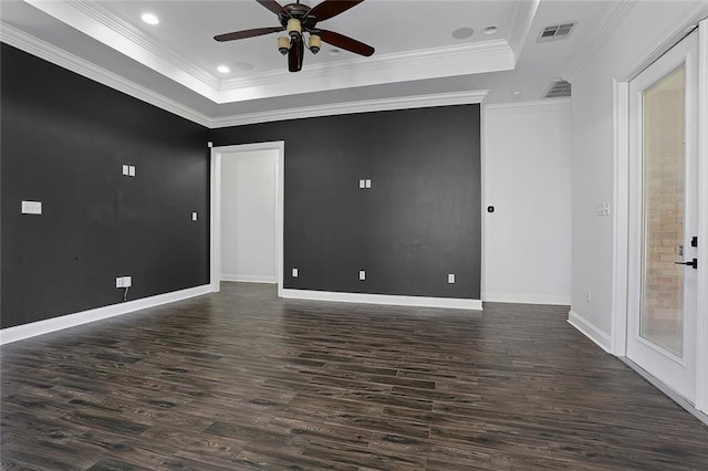 spare room featuring visible vents, a raised ceiling, dark wood finished floors, and a ceiling fan