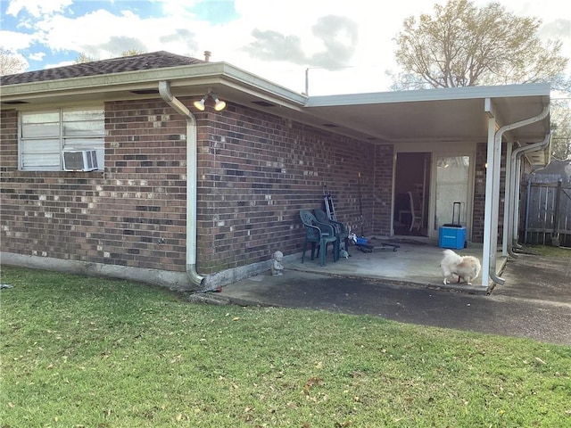 rear view of property featuring brick siding, fence, a lawn, cooling unit, and a patio area