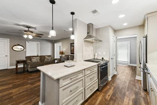 1913 Satsuma St, Metairie, LA 70001 - kitchen with appliances with stainless steel finishes, wall chimney range hood, light countertops, ceiling fan, and pendant lighting