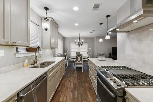 1913 Satsuma St, Metairie, LA 70001 - kitchen with stainless steel appliances, wall chimney range hood, a sink, dark wood-type flooring, and light countertops