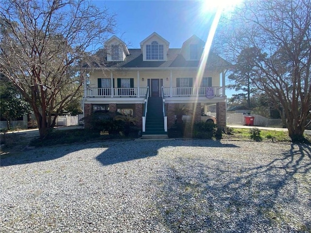 beach home featuring stairway, a porch, and fence