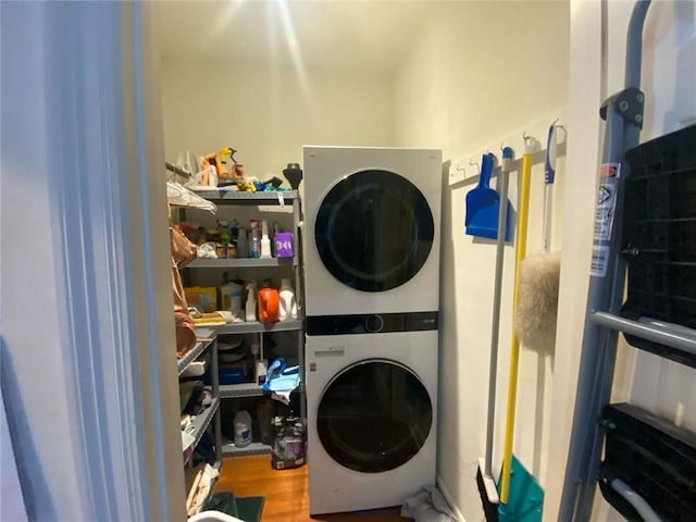 laundry area with laundry area, wood finished floors, and stacked washer / drying machine