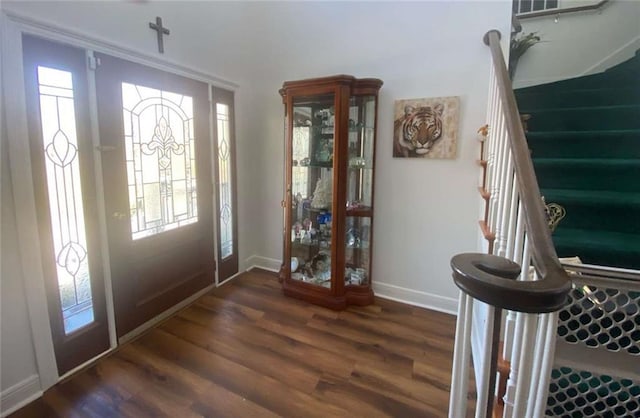 entrance foyer with stairs, dark wood-type flooring, and baseboards