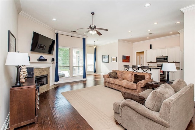 living room featuring a high end fireplace, ornamental molding, a ceiling fan, and dark wood-style flooring