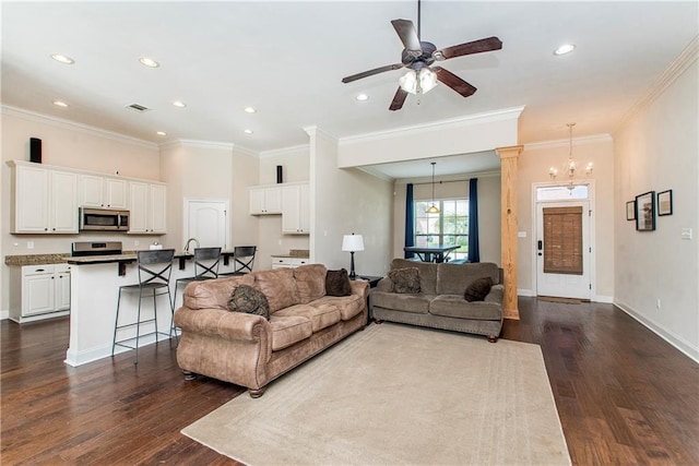 living room with visible vents, ceiling fan with notable chandelier, baseboards, and dark wood-style flooring