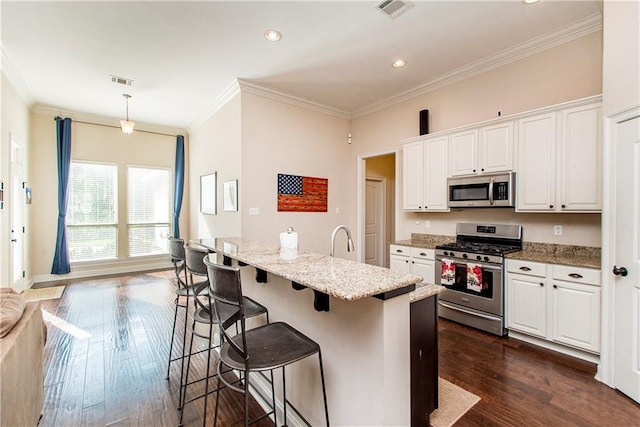 kitchen with stainless steel appliances, visible vents, white cabinets, and dark wood-style flooring