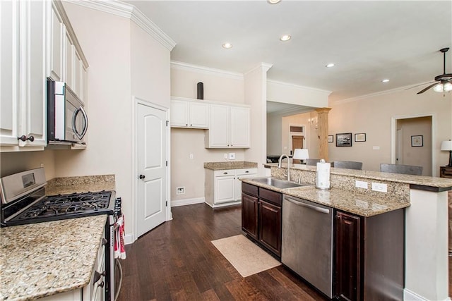 kitchen featuring an island with sink, a sink, dark wood-type flooring, white cabinets, and appliances with stainless steel finishes