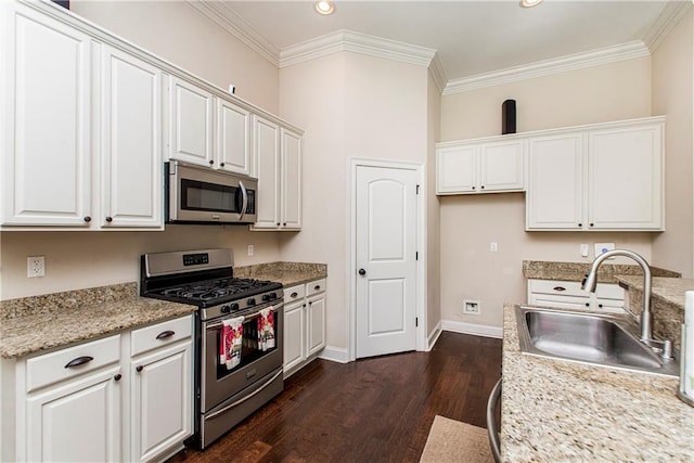 kitchen featuring baseboards, ornamental molding, a sink, dark wood-type flooring, and appliances with stainless steel finishes