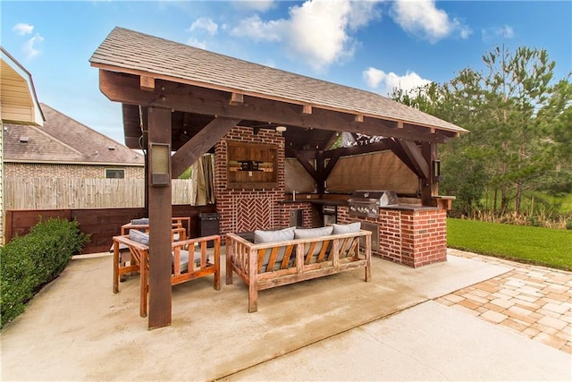 view of patio / terrace featuring an outdoor living space, fence, a gazebo, a grill, and an outdoor kitchen