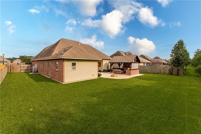 rear view of property featuring brick siding, a lawn, a fenced backyard, an outdoor fireplace, and a patio