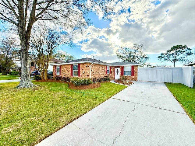 ranch-style house with concrete driveway, fence, brick siding, and a front yard