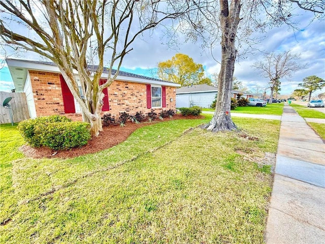 view of front facade with a front yard, fence, and brick siding