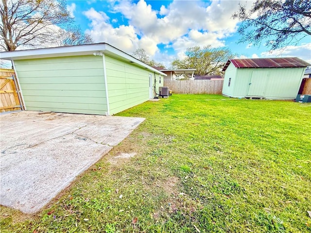 view of yard featuring a storage unit, an outdoor structure, central AC, and a fenced backyard