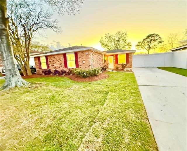 ranch-style home with a front yard, fence, and brick siding